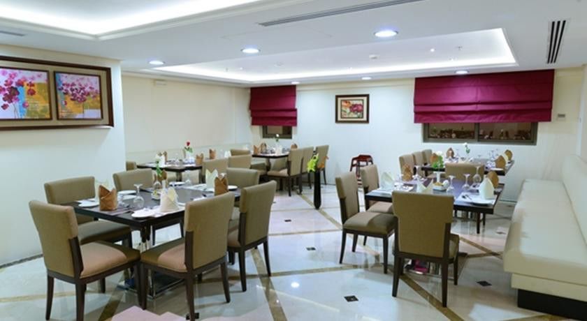 Al Aqeeq Madinah Hotel Medina Exterior foto The photo shows a well-decorated restaurant interior. It features several tables arranged neatly throughout the space, each set with chairs and tableware, including plates, glasses, and napkins. The flooring is a polished stone surface with a stylish