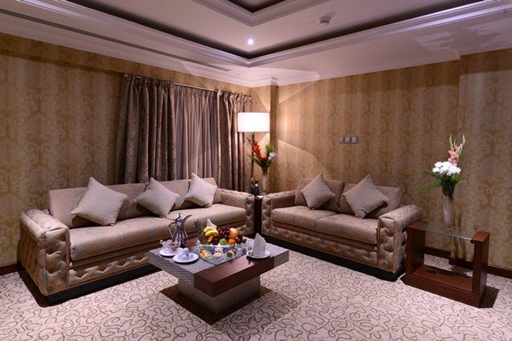 Al Aqeeq Madinah Hotel Medina Exterior foto The photo depicts a well-decorated living room. It features two elegant sofas with decorative pillows, positioned across from each other. A coffee table is centered between them, adorned with a variety of fruits and possibly some snacks or beverages.